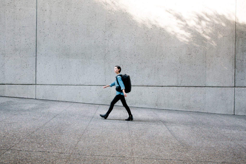 Woman walking across grey cityscape