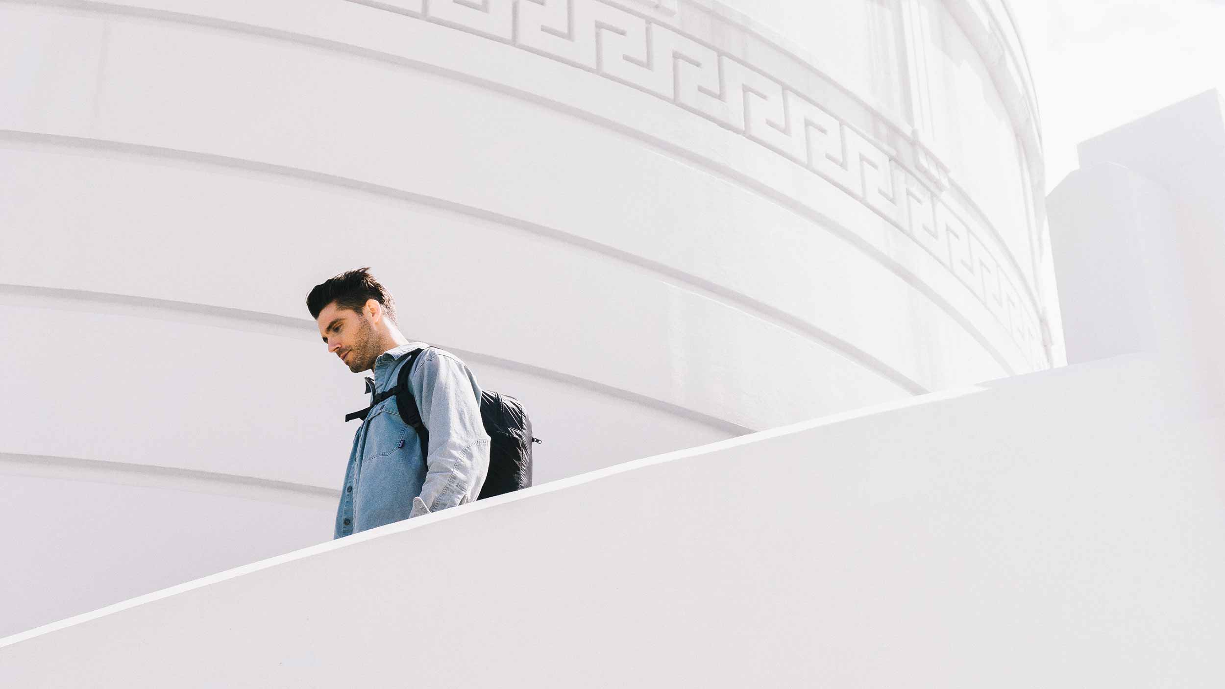 Man walking down stairs wearing backpack