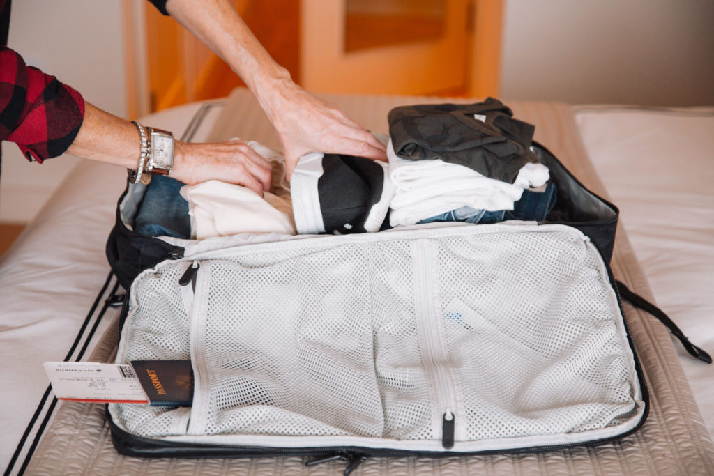 Man packing shoes into a travel backpack