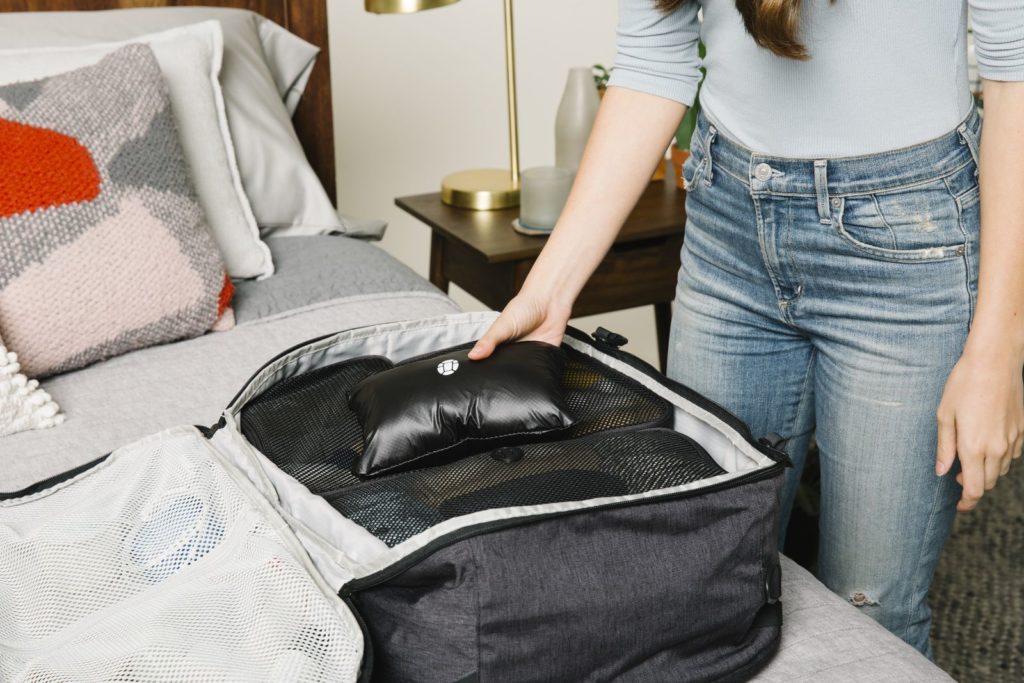 Woman packing a travel backpack, packing cubes, and packable daypack