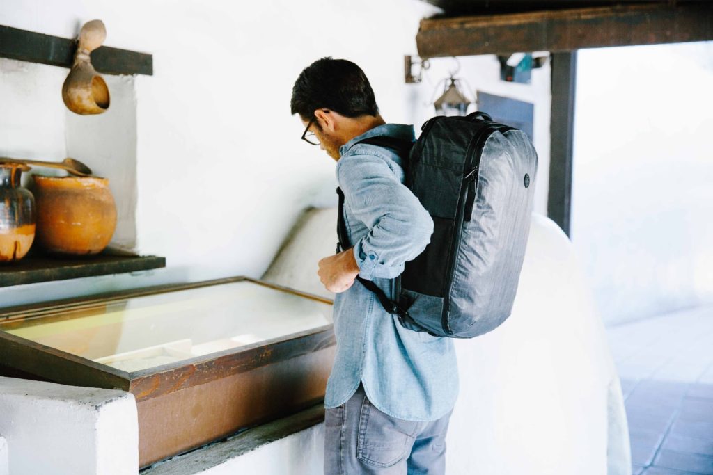 Man wearing a travel backpack looking at an exhibit