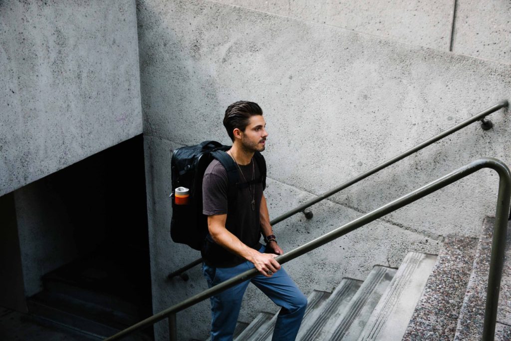 Man wearing a travel backpack walking up stairs