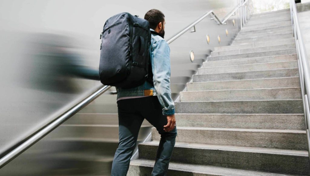 Man walking up stairs with a travel backpack