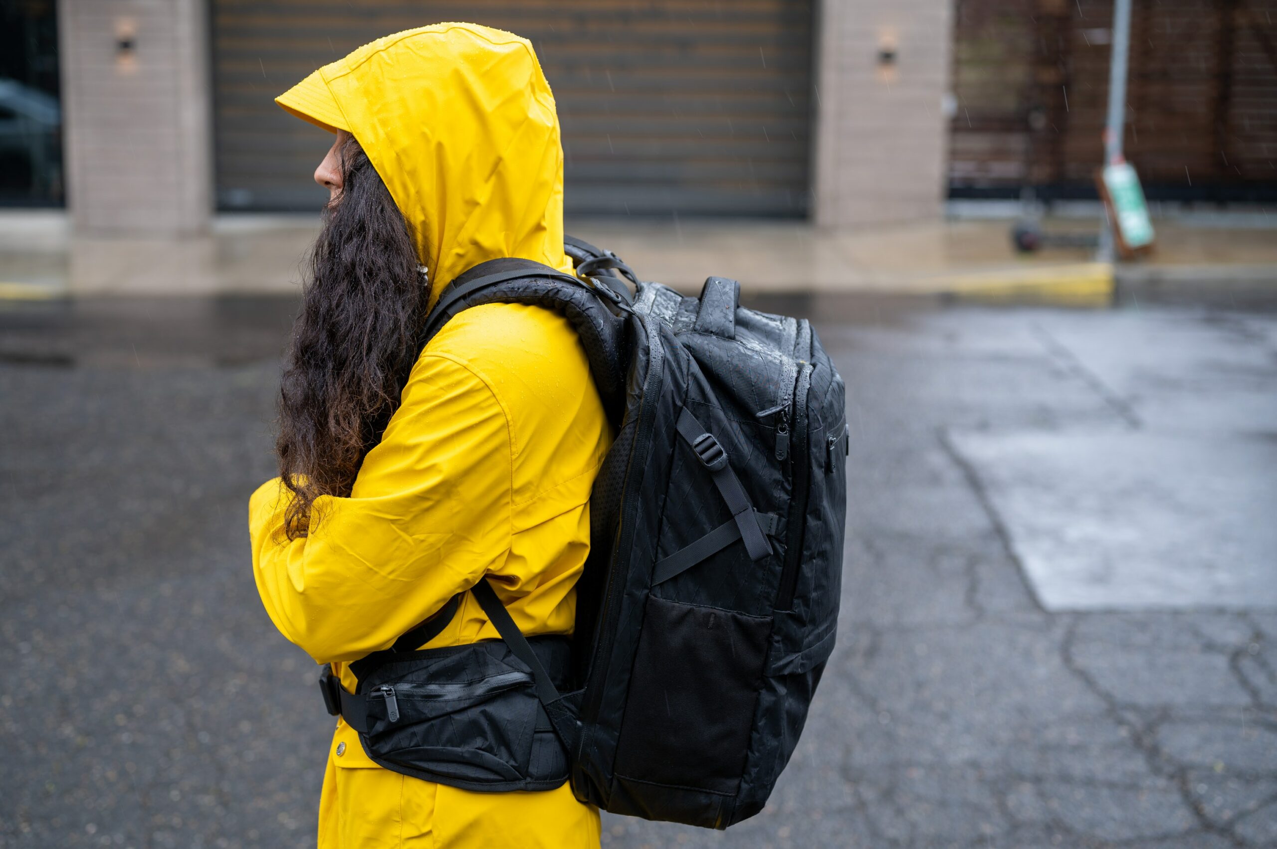 Woman wearing a yellow rain coat and water-resistant travel backpack